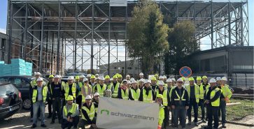 Group photo of employees in front of the aircraft hangar construction site in Brnik