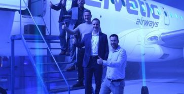 Company team standing next to an aircraft in the hangar at Brnik Airport during the opening event.