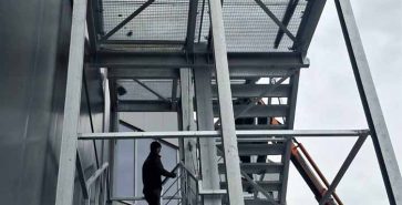 Metal staircase next to an industrial building during steel structure installation.